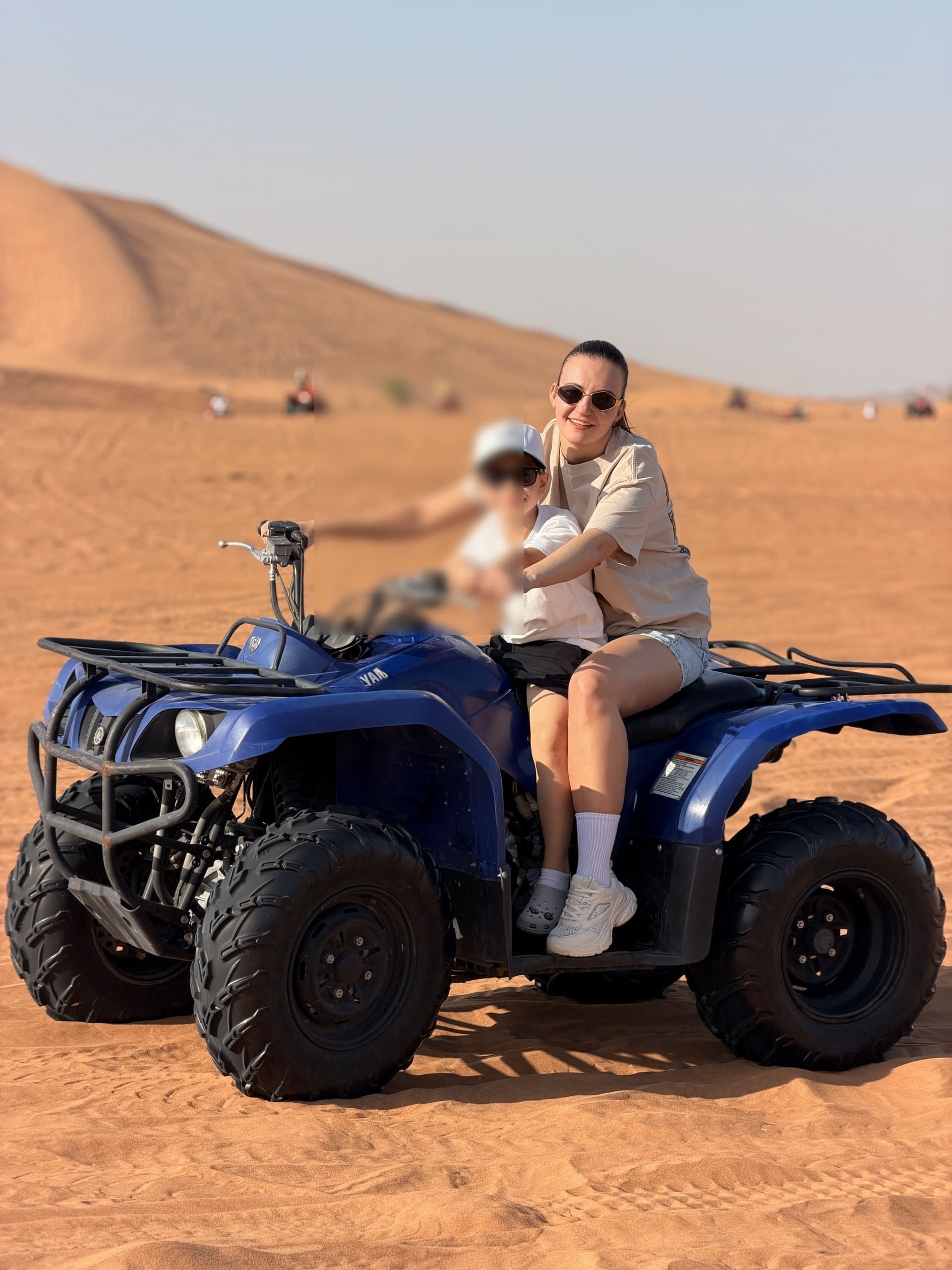 Mother and child sharing a quad bike on red sand at a Dubai desert safari