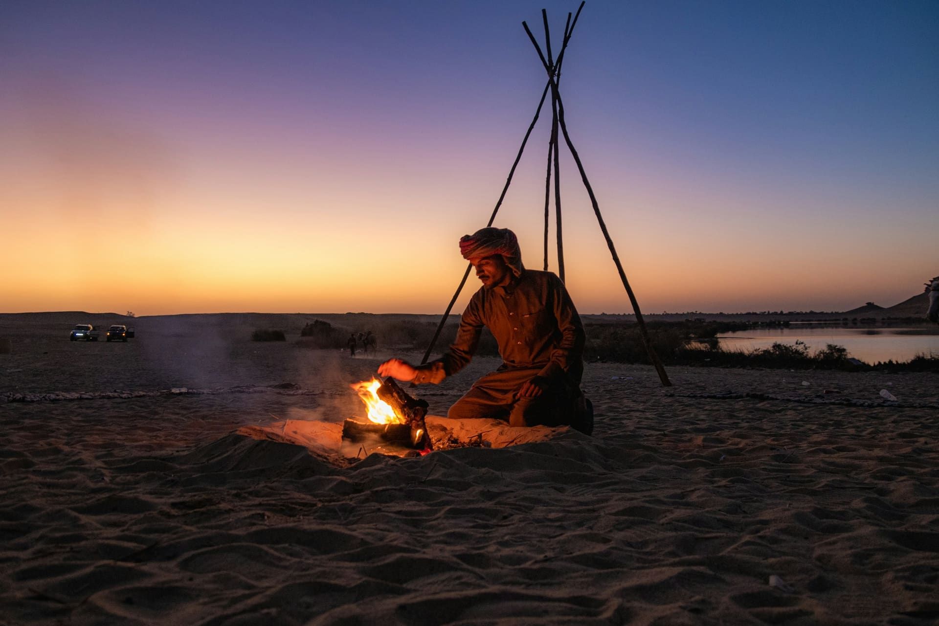 Private campfire tended at dusk beside a desert oasis on a luxury safari