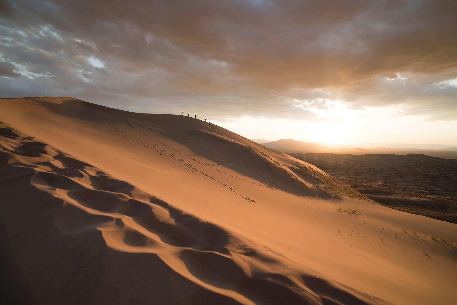 A 4x4 convoy traversing the Lahbab dunes at dawn outside Dubai with the rising sun behind the ridge