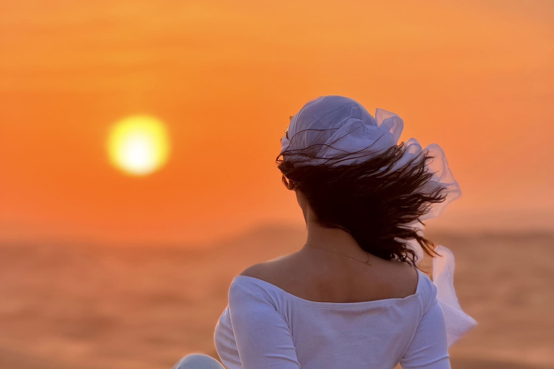 Guest watching the sunset over the Lahbab dunes on an evening desert safari in Dubai