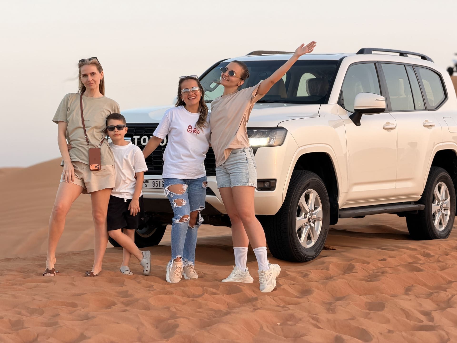 Family of four beside a white Toyota Land Cruiser at dusk in the desert