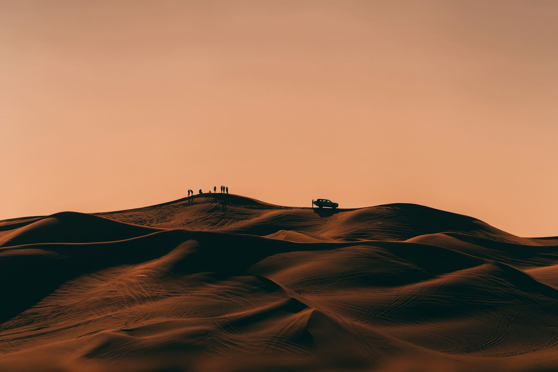 Dusk over the open Lahbab dunes with a lone safari 4x4 on the ridge line