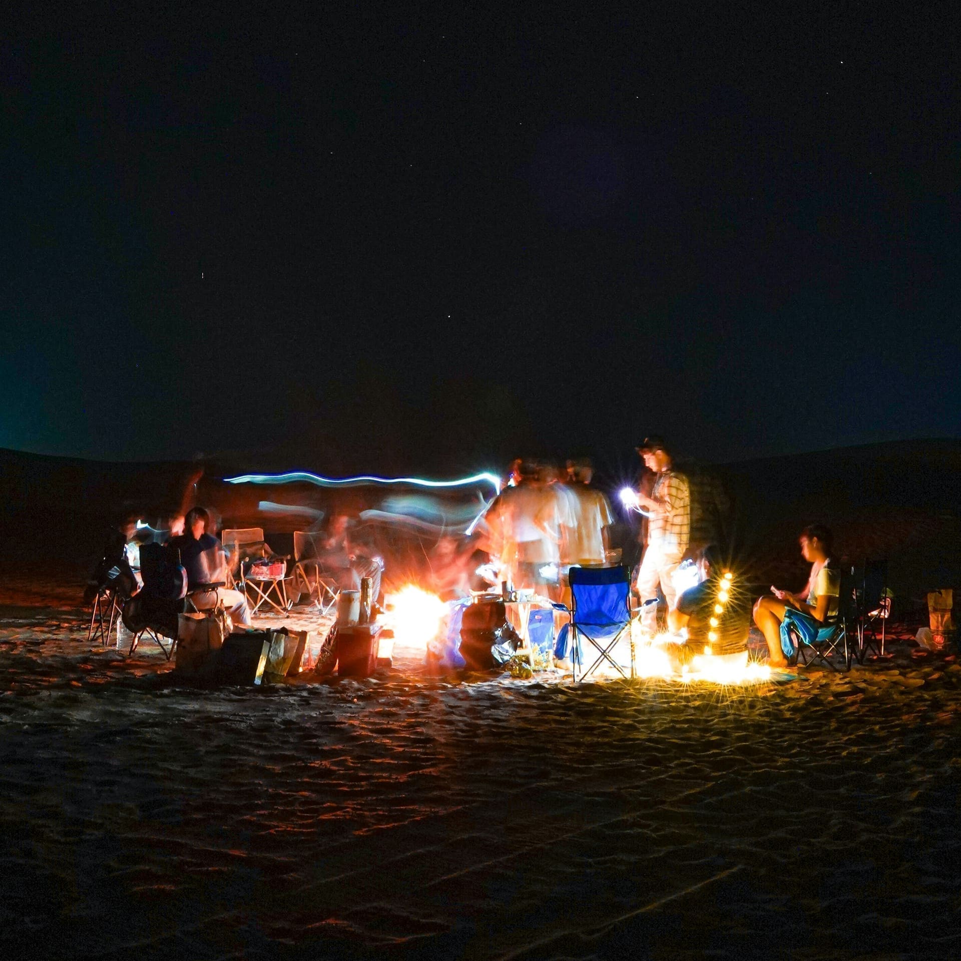 Family gathered around a Dubai desert BBQ camp at dusk