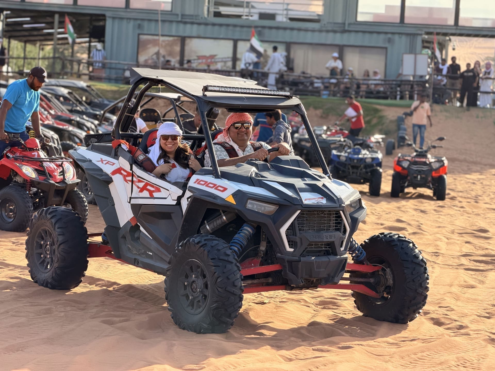 Two guests in a white Polaris dune buggy on the desert sand