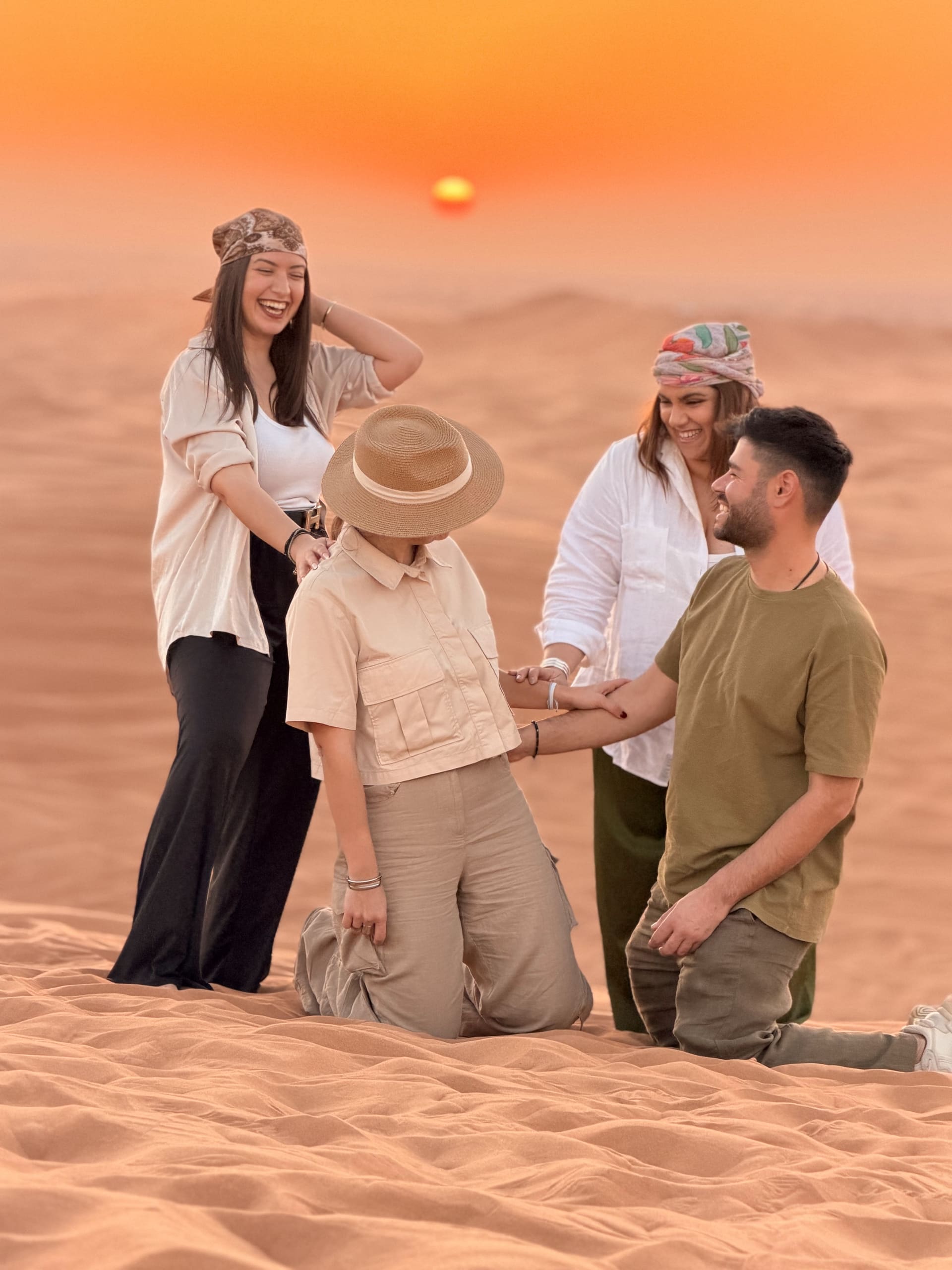 Four guests at golden hour on a red dune ridge at sunset