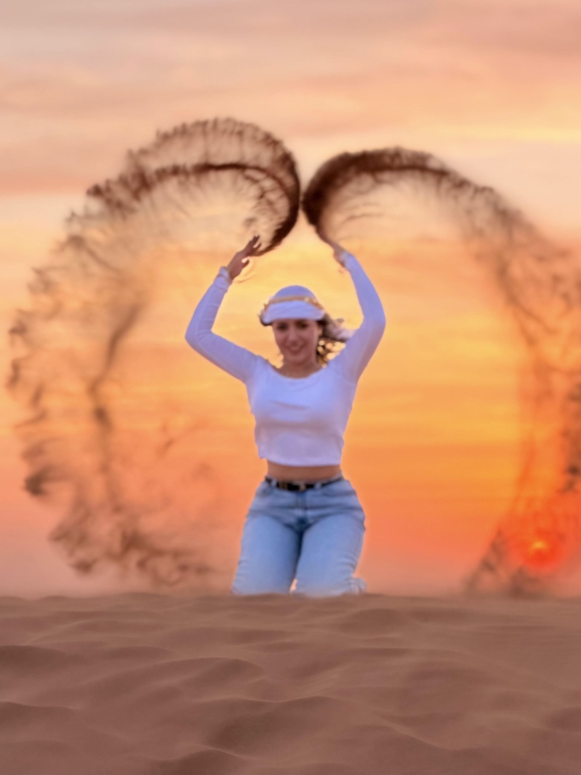 A guest tossing arcs of sand into the air at sunset on a Dubai dune