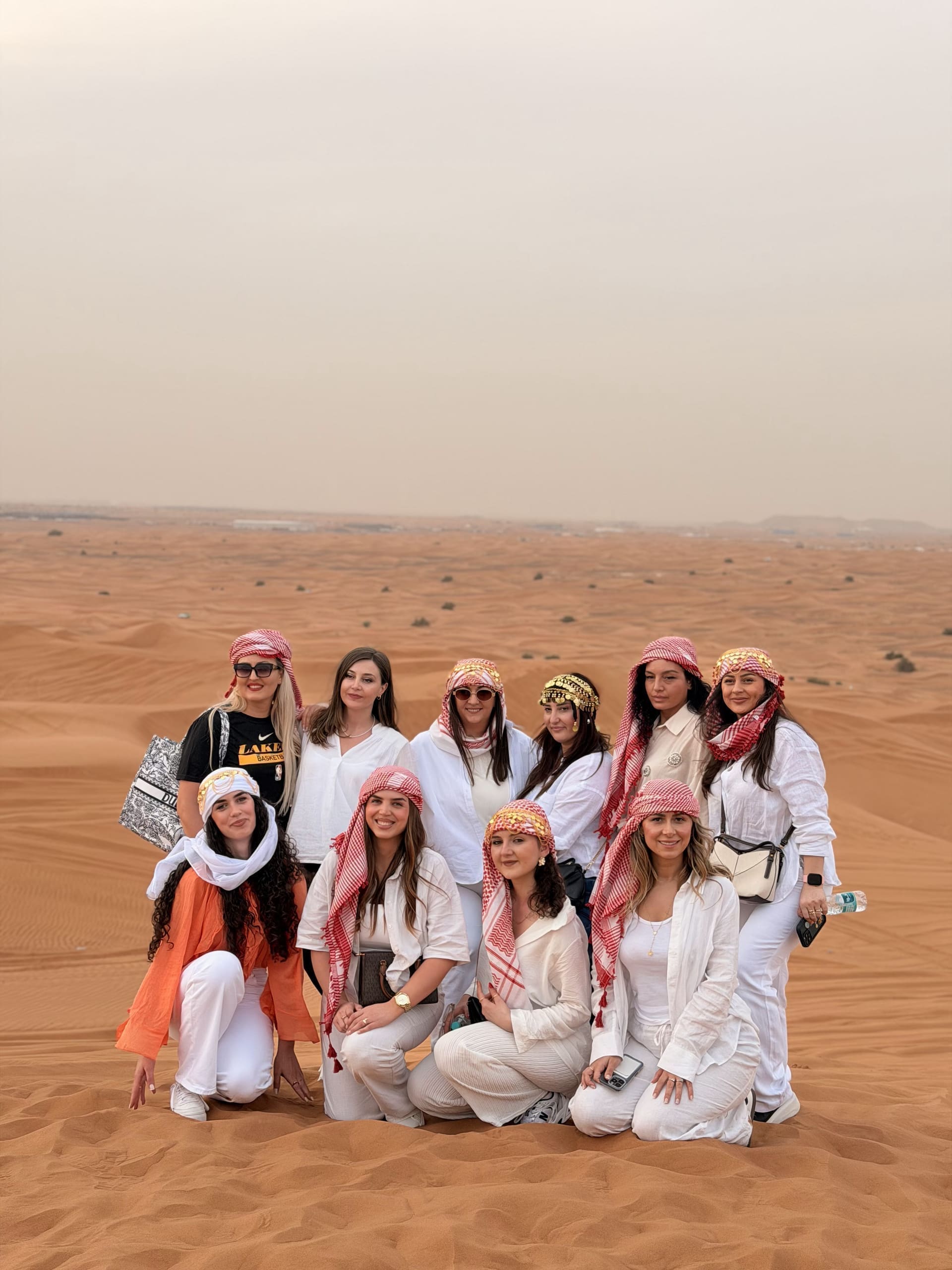 A group of guests posing together on the red sand dunes