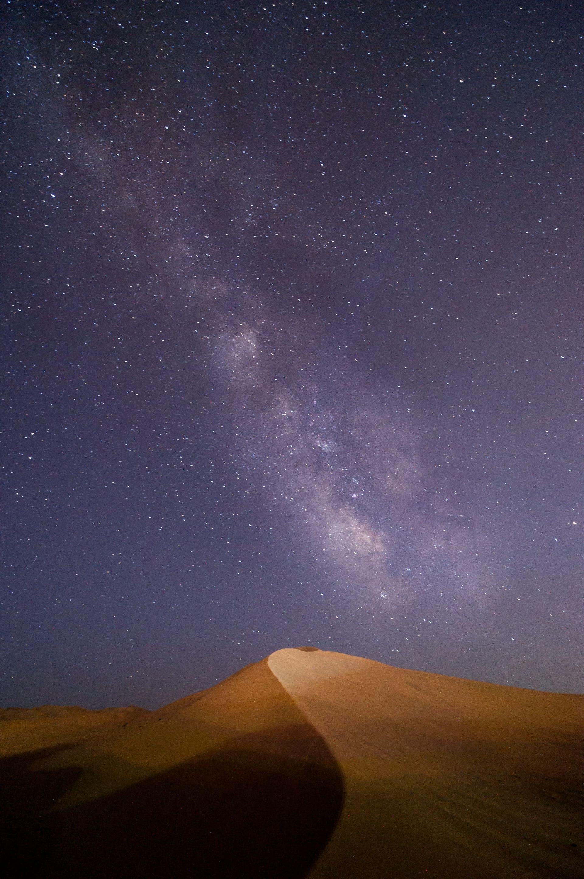 The Milky Way arching over a Dubai desert ridge after midnight