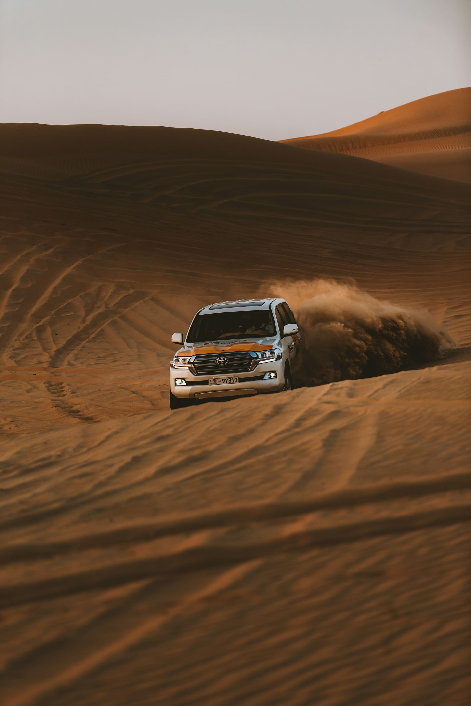Toyota Land Cruiser cresting a red Lahbab dune during dune bashing