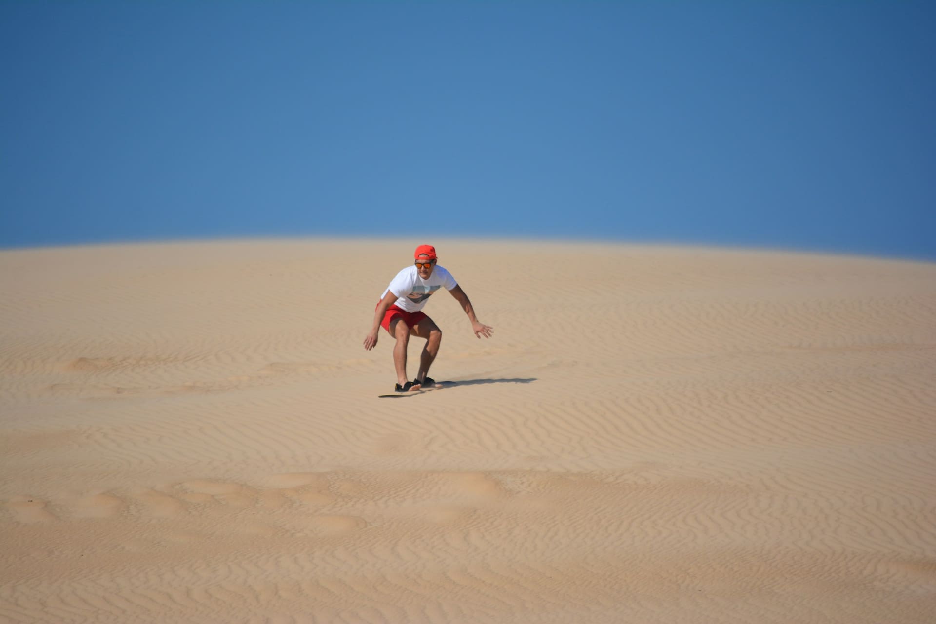 Sandboarder sliding down a dune face